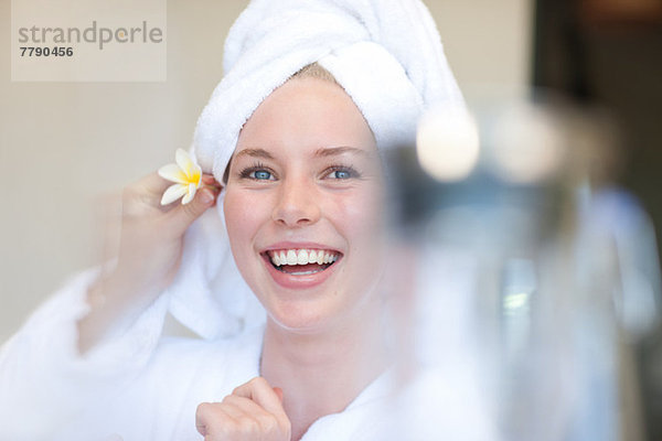 Junge Frau mit Handtuch am Kopf und Blume hinter dem Ohr