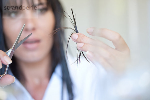 Mittlere erwachsene Frau mit Schere und Haaren