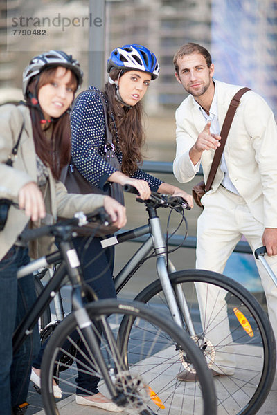 Junge Frauen mit Fahrrädern fragen den jungen Mann nach dem Weg.