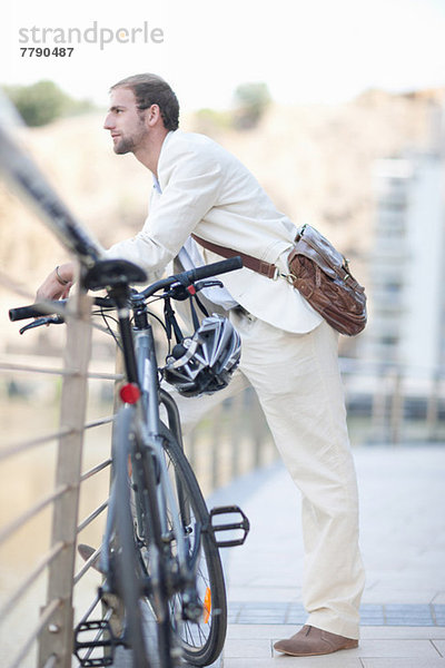 Junger Mann am Geländer mit Fahrrad
