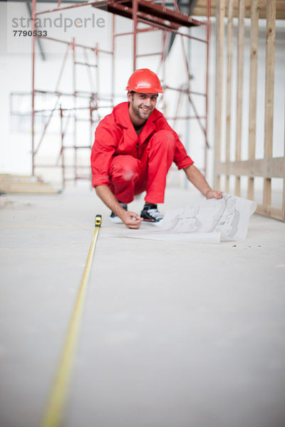 Bauherr mit Blaupause Messboden auf der Baustelle