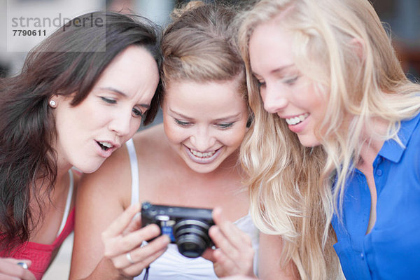 Drei junge Frauen beim Betrachten von Fotos