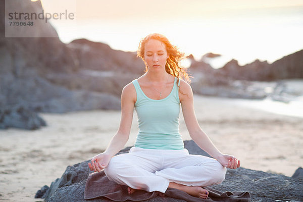 Junge Frau beim Yoga am Strand