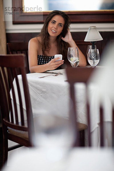 Junge Frau im Restaurant mit Smartphone