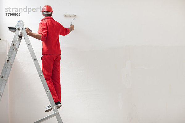 Dekorateur auf Stehleiter Malerei weiße Wand