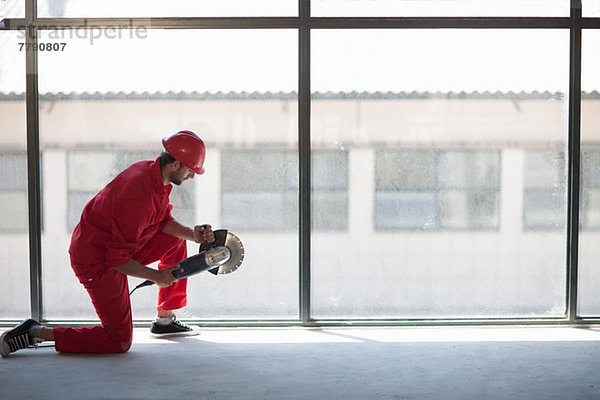 Arbeiter kniend vor dem Fenster mit Kreissäge