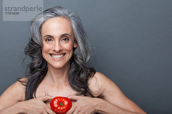 Reife Frau mit roter Tomate