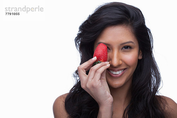 Junge Frau bedeckt Auge mit Erdbeere