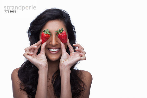 Junge Frau  die die Augen mit Erdbeeren bedeckt