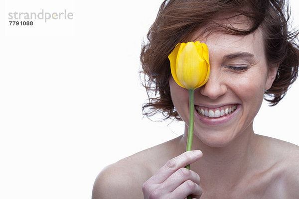 Junge Frau hält gelbe Tulpe mit geschlossenen Augen
