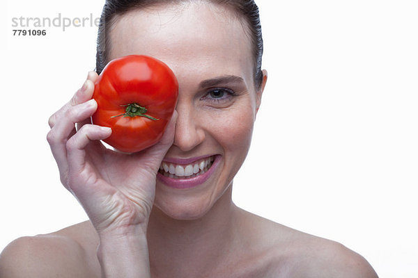 Junge Frau bedeckt Auge mit roter Tomate