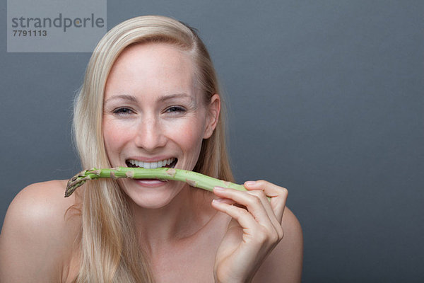 Junge Frau beißt Spargel