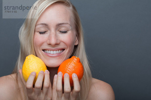 Junge Frau hält Orange und Zitrone  Augen geschlossen