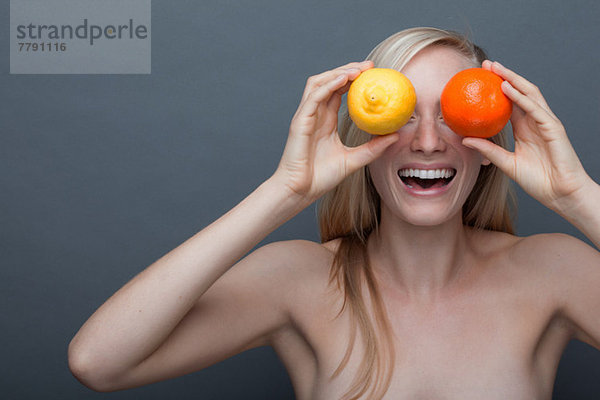 Junge Frau bedeckt die Augen mit Orange und Zitrone