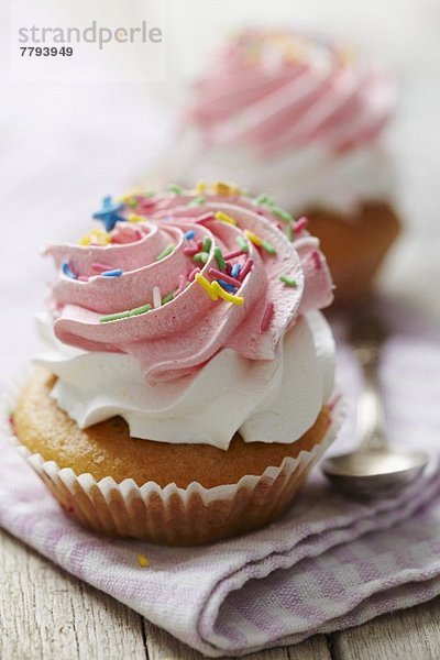 Cupcake mit Sahne  Himbeercreme und bunten Zuckerstreuseln