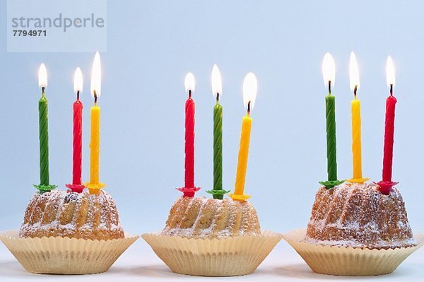 Drei Napfkuchen mit brennenden Kerzen zum Geburtstag