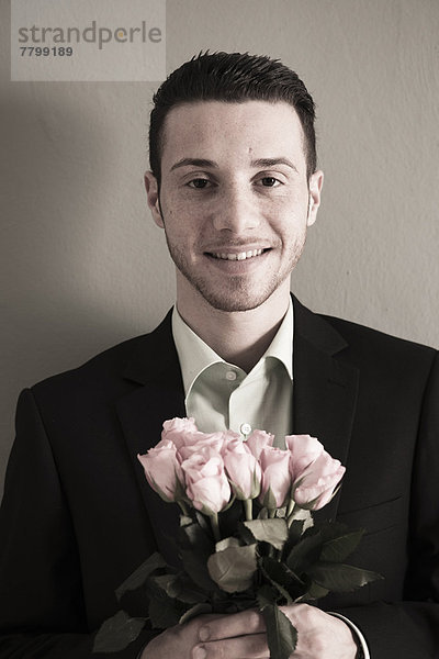 Studioaufnahme  Blumenstrauß  Strauß  Portrait  Mann  Blick in die Kamera  halten  pink  Rose  jung