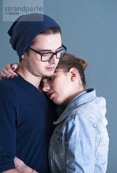 Portrait of Young Couple Embracing  Studio Shot on Blue Background