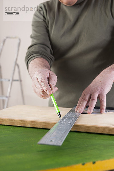 Man Measuring Lumber  Woodworking Project  in Studio