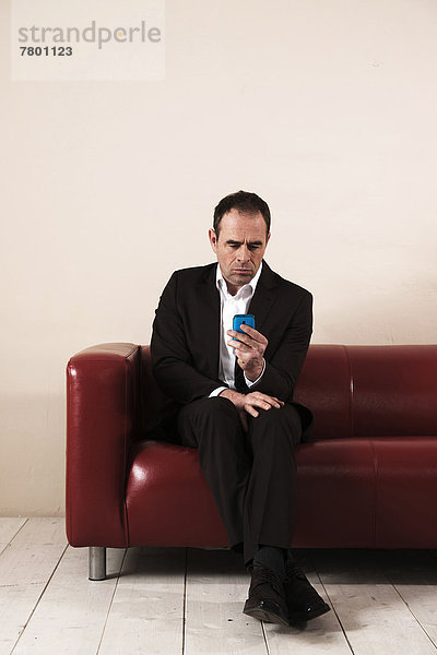 Handy  sitzend  Mann  sehen  Couch  reifer Erwachsene  reife Erwachsene
