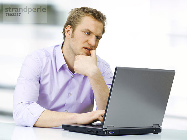 Geschäftsmann am Laptop  konzentriert  knabbert an seinem Fingernagel
