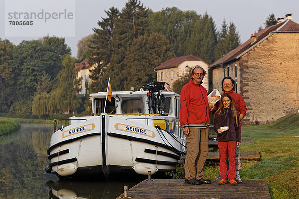 Mann  Frau und Mädchen mit Broteinkauf am frühen Morgen  vor Hausboot auf dem Canal des Vosges  früher Canal de l?Est