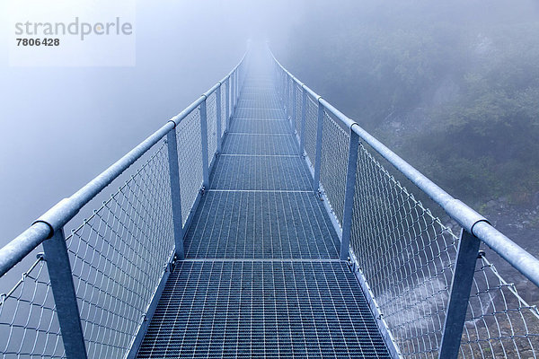 Stahlbrücke im Nebel über einen Alpenbach