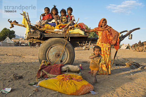 Vier Kinder sitzen auf einem Kamelkarren  eine Frau und ein kleiner Junge stehen daneben  Kamelmarkt