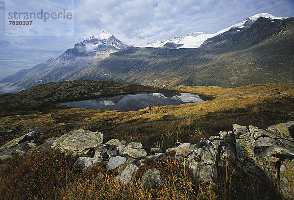 Wanderer am Bergsee Lac Blanc  hinten der Dent Parrachée  der Dôme de l'Arpont und die Vanoise-Gletscher