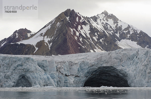 Gletschertor  Ausfluss eines Schmelzwasserbaches unter dem Gletscher  im Samarinbreen  hinten der Berg Tindegga