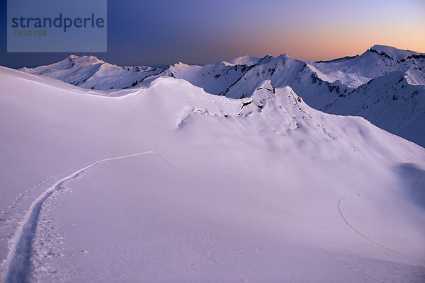 Berglandschaft mit Skispur im unberührten Neuschnee in Morgendämmerung