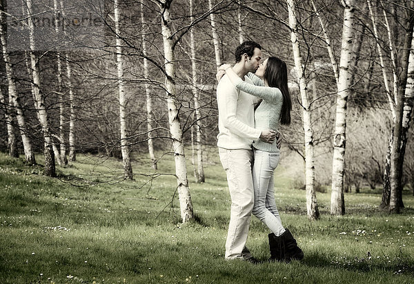 Junges Paar küsst sich in Birkenwald