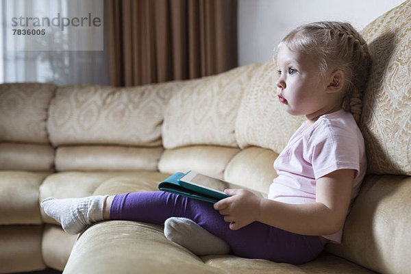 Transfixed Mädchen auf Sofa mit digitalem Tablett