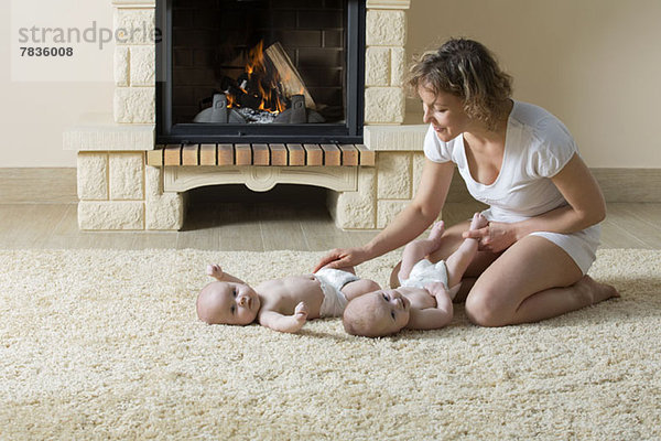 Mutter und Töchter auf Teppich vor dem Feuer