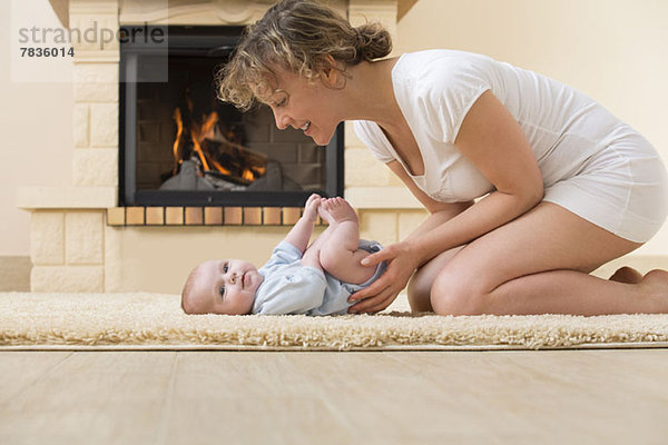 Mutter und Tochter auf Teppich vor dem Feuer
