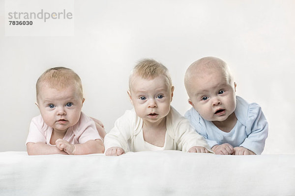 Drei Babys machen lustige Gesichter