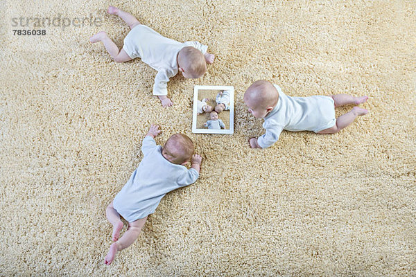 Drei Babys betrachten ein Bild von sich selbst auf einem digitalen Tablett.
