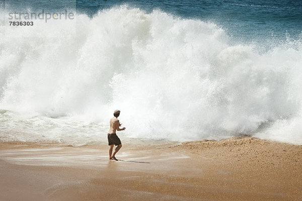 Mann vor großer Welle am Strand in La Graciosa  Kanarische Inseln  Spanien