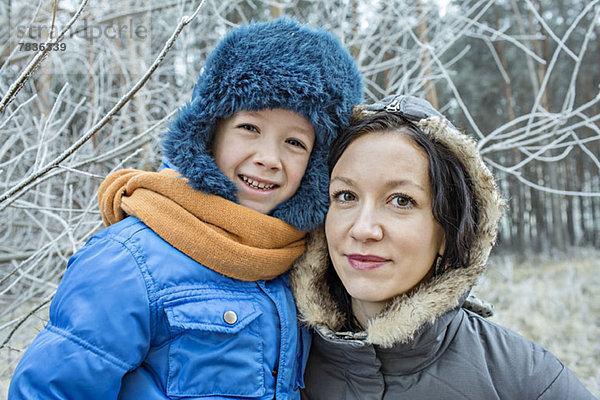 Eine fröhliche Mutter und Sohn in warmer Kleidung im Freien im Winter