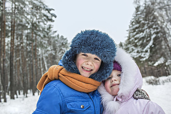 Ein fröhliches Geschwisterpaar in warmer Winterkleidung im Freien im Winter