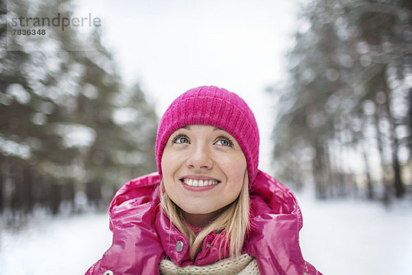 Eine schöne Frau mit Strickmütze  die nach oben schaut  im Winter draußen.