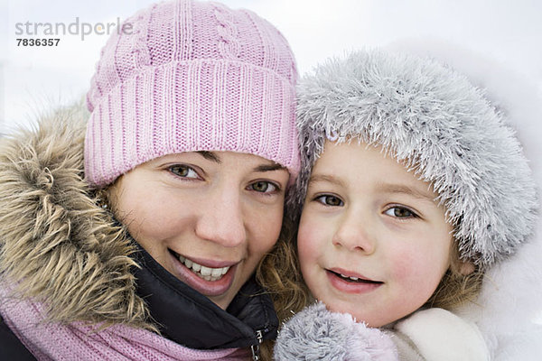 Eine fröhliche Mutter und Tochter in warmer Kleidung im Freien im Winter