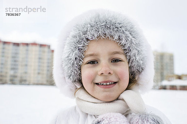 Ein fröhliches junges Mädchen  das im Winter warme Kleidung trägt
