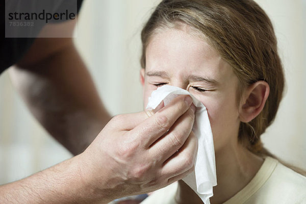 Vater wischt die Nase der Tochter mit Gewebe ab.