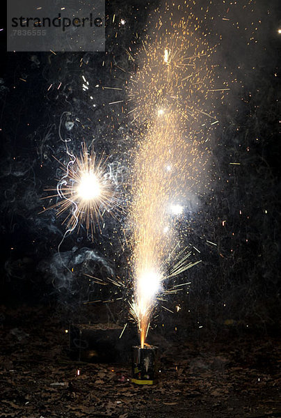 Funken und Rauch aus einem Feuerwerk  das auf einem Bürgersteig explodiert.