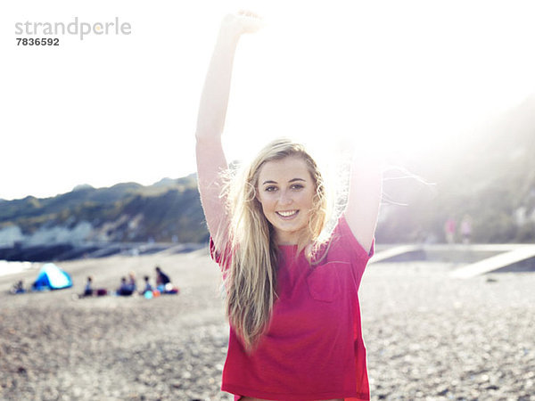 Eine junge Frau  die sich im Sonnenlicht am Strand ausstreckt.