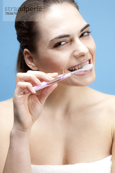 Eine lächelnde junge Frau beim Zähneputzen