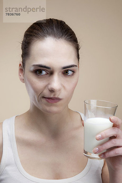 Eine junge Frau  die ein Gesicht macht  nachdem sie einen Schluck Milch getrunken hat.