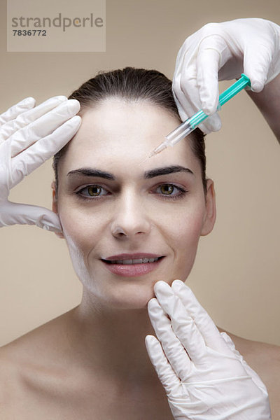 Eine lächelnde junge Frau  die Botox-Injektionen erhält.