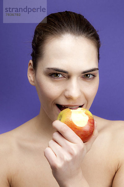 Eine lächelnde junge Frau beim Apfelessen